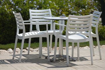 Four white plastic chairs surround a matching table on a patio