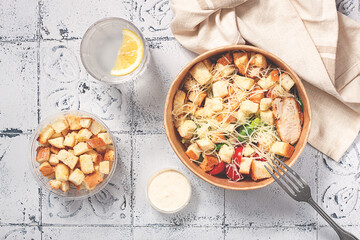 Caesar salad in a paper container, take it on the way, with sauce and croutons, on the table, snack, no people,