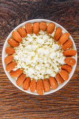 Top view of fresh cottage cheese with almonds in white bowl.