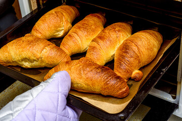 We take the baking tray with ready croissants on baking paper out of the oven.