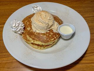 Delicious fluffy pancakes with a scoop of ice cream on top and tres leches (three milks) sauce for pouring on top.