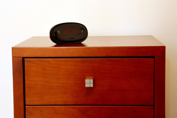 Nightstand with a drawer and an alarm clock on top.