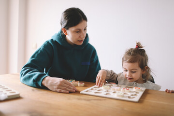 Mother teaches her girl letters through play