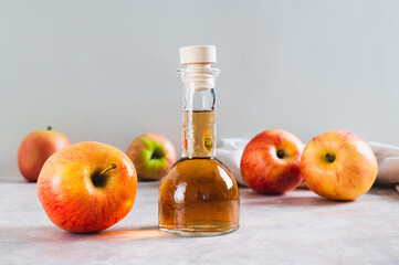 Apple cider vinegar in a bottle and fresh apples on the table