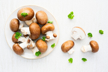 Raw brown mushrooms in a white plate, with freshly cut slices.