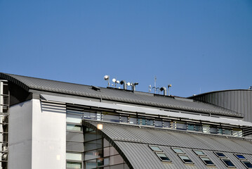 Fototapeta premium The roof of the building is covered with metal, ventilation pipes, antennas for telephony and cellular communication, internet and manzandra windows, office building top