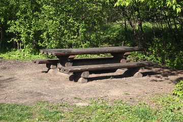 Retro style wooden table and benches as a cozy place for outdoor picnic in the shade in the forest