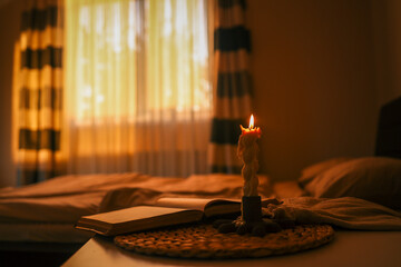 Extinguished twisted candle releasing smoke beside an open book on a cozy bed, with warm ambient...