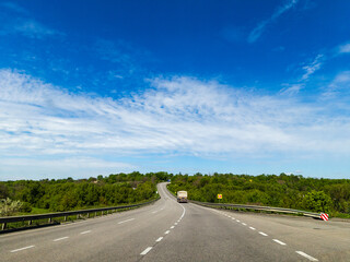 A truck driving down a highway with trees in the background