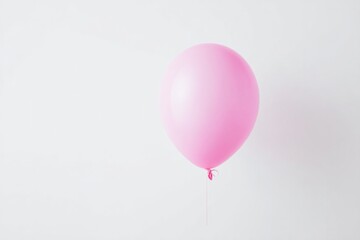 single bright minimalistic pink balloon floats conspicuously in middle of vast white background