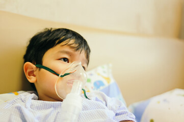 Boy 4 years old , inhale medication by inhalation mask to cure Respiratory Syncytial Virus (RSV) on hospital bed. Admitted patient boy inhalation therapy.