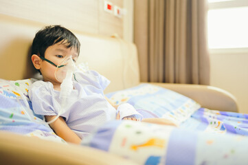 Boy 4 years old , inhale medication by inhalation mask to cure Respiratory Syncytial Virus (RSV) on hospital bed. Admitted patient boy inhalation therapy.