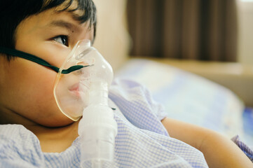 Boy 4 years old , inhale medication by inhalation mask to cure Respiratory Syncytial Virus (RSV) on hospital bed. Admitted patient boy inhalation therapy.