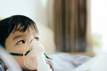 Boy 4 years old , inhale medication by inhalation mask to cure Respiratory Syncytial Virus (RSV) on hospital bed. Admitted patient boy inhalation therapy.