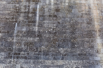 Wall of ancient castle bastion clad with stone blocks, fragment
