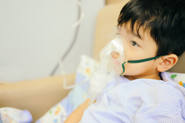 Boy 4 years old , inhale medication by inhalation mask to cure Respiratory Syncytial Virus (RSV) on hospital bed. Admitted patient boy inhalation therapy.