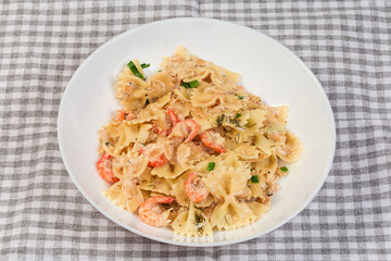 Cooked butterfly shaped pasta with boiled shrimp tails on dish