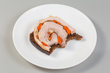 Partly bitten open sandwich with baked pork belly roll slice