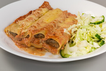 Baked pasta cannelloni stuffed with meat filling, close-up