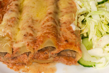 Baked pasta cannelloni stuffed with meat filling, close-up