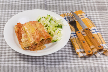 Serving of baked pasta cannelloni stuffed with meat filling