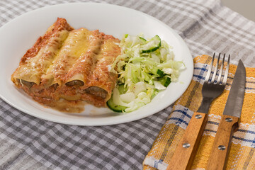 Serving of baked pasta cannelloni stuffed with meat filling