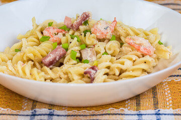 Spiral pasta with boiled seafood in white souse close-up