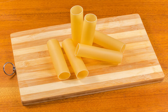 Raw large tube shaped pasta on cutting board on table