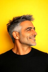 Fototapeta premium Idea of style for aging men. Fashionable men's spiky hair haircut - midlife middle eastern man with short hair. Yellow solid background. A fashionable and chic male posing elegantly.