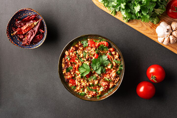 Traditional hot chili con carne in ceramic bowl on black stone table top view. Tasty homemade food concept.
