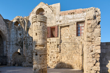 The ancient architecture of the Church of the Virgin Mary of the Burgo in Rhodes, Greece, showcasing medieval stone walls and structures.
