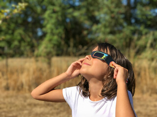 Young child safely observing a rare solar eclipse using special viewing glasses