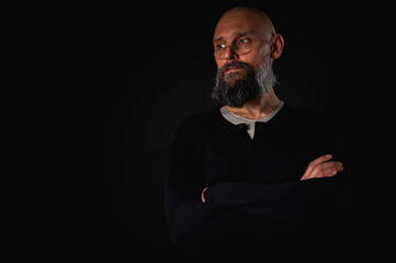 Thoughtful mature man with glasses and beard posing in studio with dramatic lighting. Conceptual...