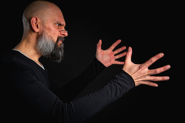 Dramatic portrait of an energetic man with a beard and glasses, reaching to the side emotionally, trying to grab something. Subtle lighting, emotional expression, dark background, mysterious concept.