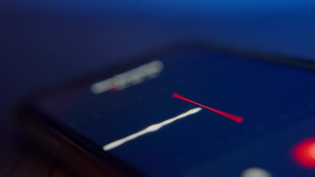Close up on sound wave on audio recording app screen on phone in dark room. Secretly grabbing conversation and voice in room by spy or mole whistleblower. Evidence in criminal investigation testimony