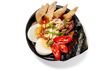 Ramen with chicken, eggs, mushrooms, nori seaweed, chilli pepper and sesame seeds in black bowl