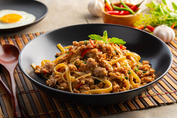 Stir fried spicy fettuccine pasta with minced pork and basil in black plate,Spaghetti Pad Kra Pao.