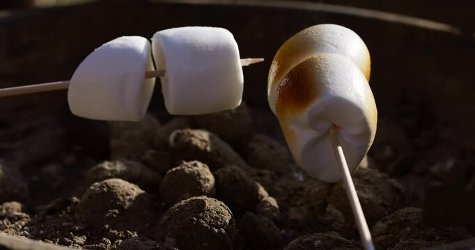 Close-up of fluffy marshmallows toasting over a hot grill, melting slightly from the heat.