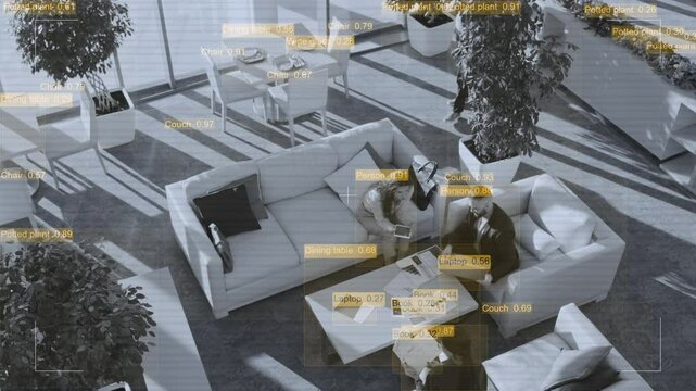 Wide shot of hidden spy camera recording and analyzing partners discussing project, viewing graphs and presentation on tablet while sitting in armchairs in hotel lobby during business trip