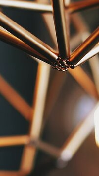 CU, slow motion: stylish golden steam-punk metal luster and light bulb hang on ceiling in spacious room against blurred background close view