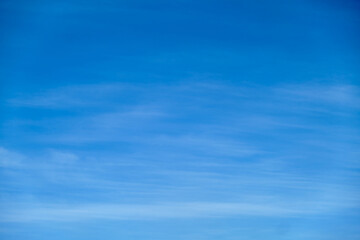 Clear blue sky with soft wispy clouds. Natural background with copy space for design and print.