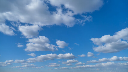 Blue sky with scattered white clouds. Natural background with copy space. Weather and atmosphere concept for design and print