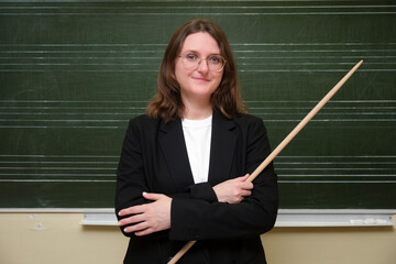 The female teacher is conducting a lesson, standing near the chalkboard and engaging her class. A...