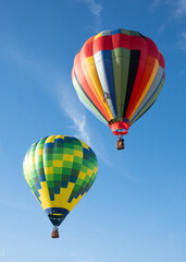 Naklejka premium A pair of giant colorful hot air balloons rise over blue skies in Northern California.