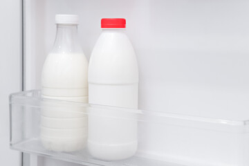There is a bottle of milk and kefir in the refrigerator