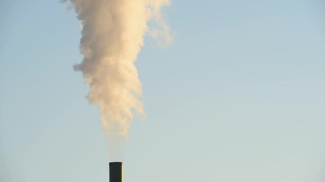 detalle de chimenea de una f&aacute;brica expulsando humo a la atm&oacute;sfera