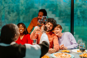 Friends toasting red wine at dinner party celebrating with pizza and wine