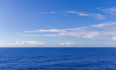 Vast Ocean Horizon Under a Clear Sky with Soft Clouds