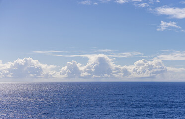 Tranquil Ocean Scene With Clear Sky and Puffy White Clouds on Horizon