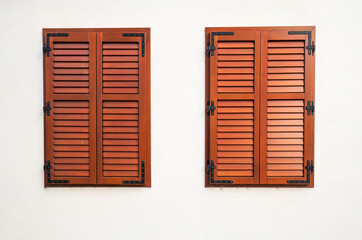 Two closed wooden window shutters on white wall
